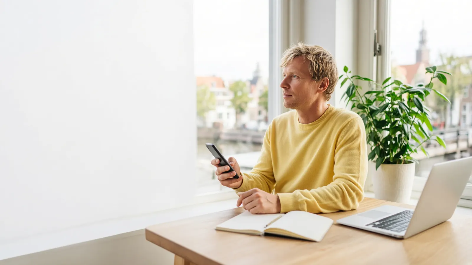 Ondernemer wacht bij het raam met zijn telefoon in de hand op antwoord